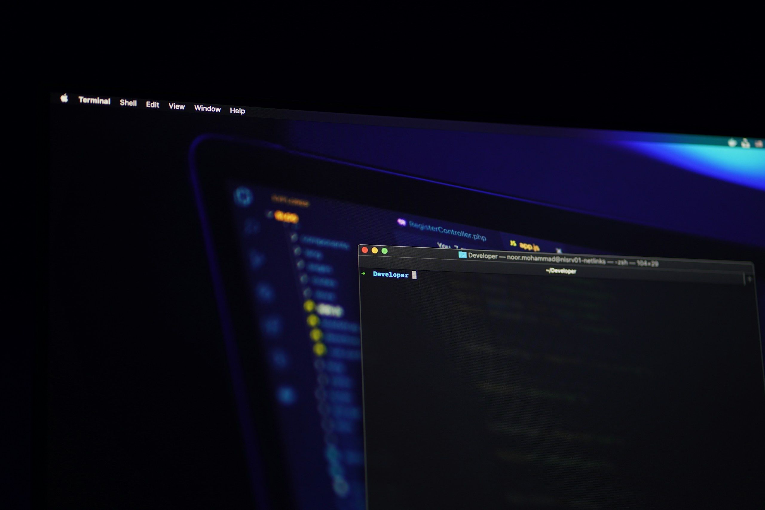 Black flat screen monitor displaying code in a dark workspace, the only light source the screen itself